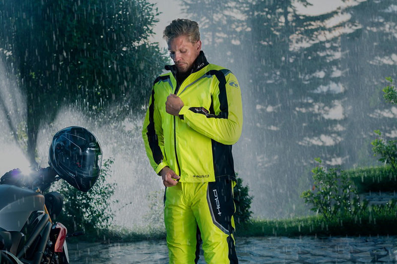 mężczyzna ubiera kombinezon przeciwdeszczowy stojąc w deszczu
