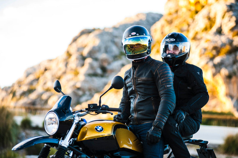 dwoje motocyklistów w klasycznych kurtkach skórzanych siedzi na motocyklu typu cruiser, w tle skały