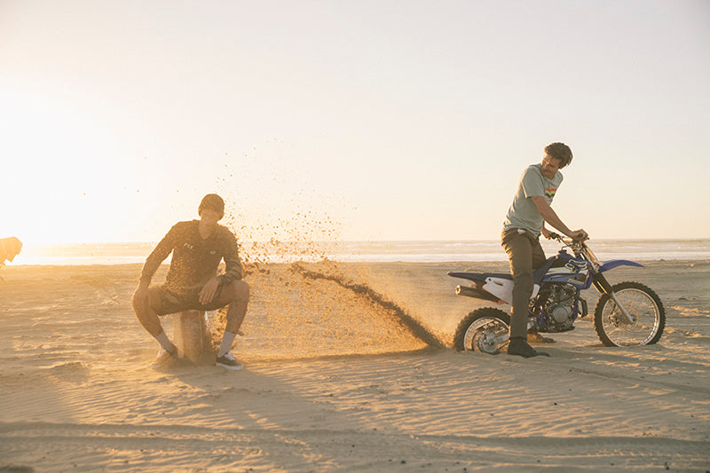 Zabawa motocyklistów na plaży w tle zachodzące słońce, mężczyzna na motocyklu typu pit bike