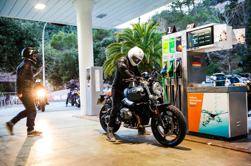 mężczyzna tankuje motocykl na stacji paliw