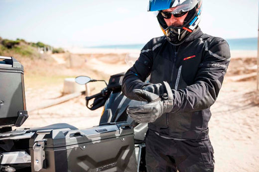 Motocyklista w kurtce Rebelhorn Hiflow III nakłada rękawicę motocyklową 