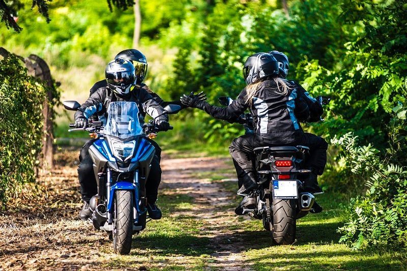 motocykliści jadący w parku pozdrawiają się