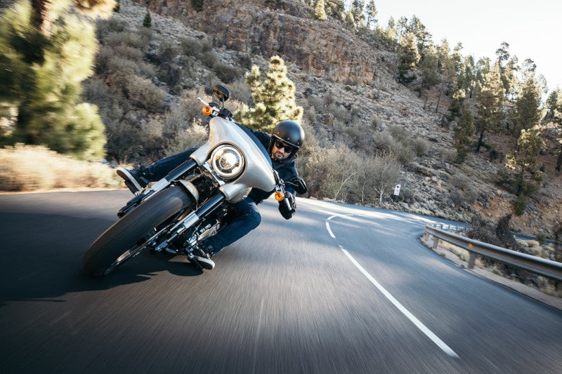 motocyklista jedzie drogą na czarnym motocyklu w czarnym kasku 
