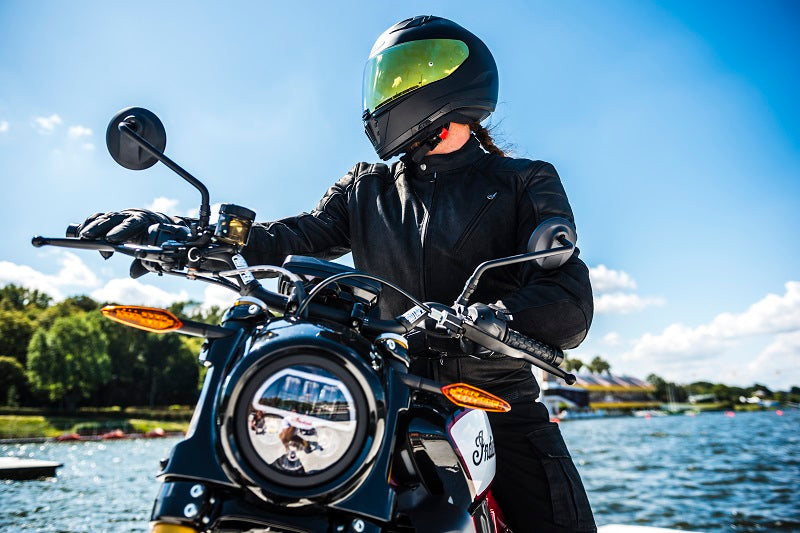 Motocyklista w kurtce skórzanej motocyklowej na motocyklu z widokiem na morze 