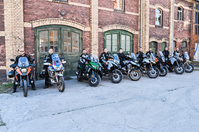 duża grupa motocyklistów stoi przy budynku z czerwonej cegły