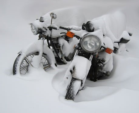 dwa motocykle stoją całe w śniegu, nieochronione przed zimą