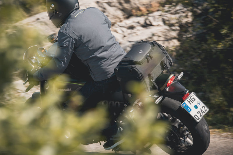 Motocyklista w kurtce motocyklowej tekstylnej i kasku na motocyklu kawasaki, wchodzący w zakręt