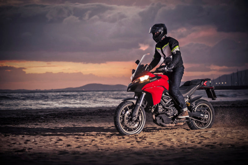 motocyklista jedzie po plaży na dutaci multistrada