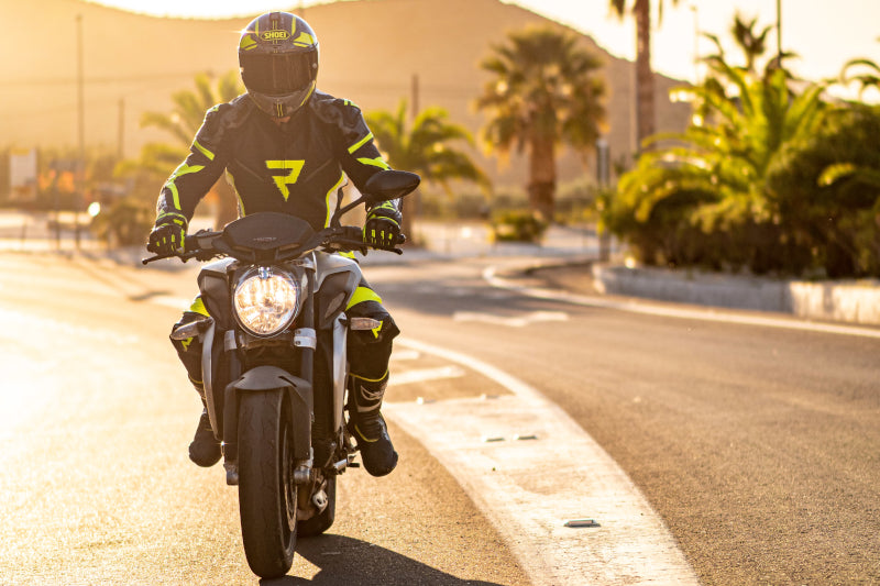 motocyklista jedzie samotnie o zachodzie słońca wśród palm
