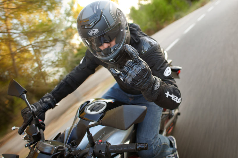 motocyklista w rękawicach Held jedzie szybko ulicą na swoim motocyklu w kasku Held