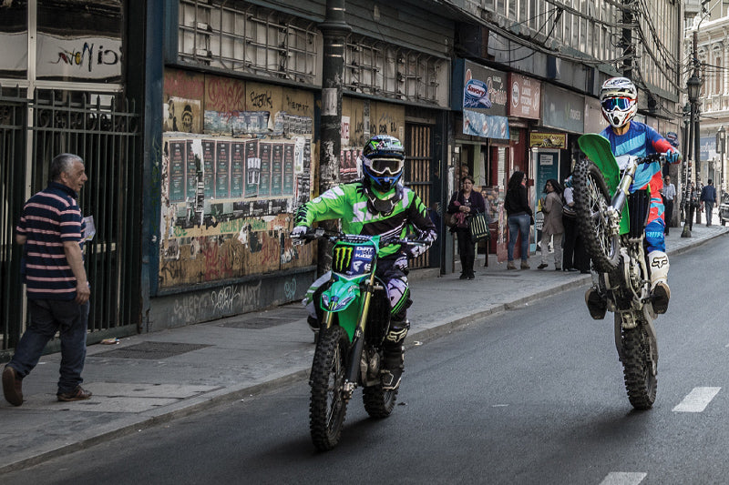 dwójka motocyklistów jedzie przez miasto, jeden na tylnym kole