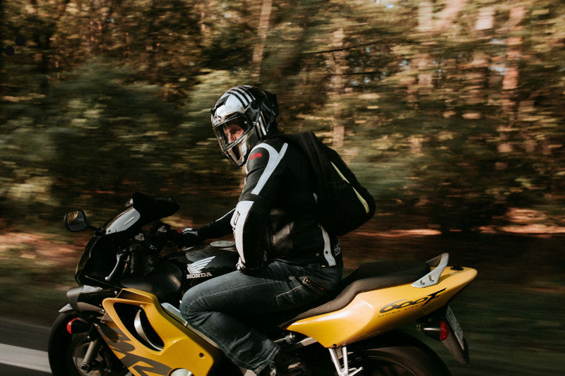 Motocyklista na żółtym motocyklu z głową obróconą w bok