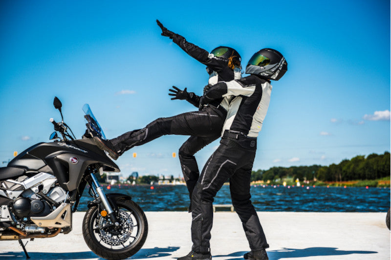 Motocyklista trzyma motocyklistę, która rwie się do motocyklu, który stoi obok