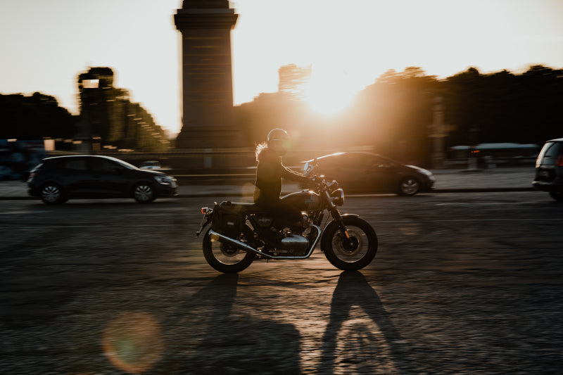 Kobieta jedzie na motocyklu przy zachodzie słońca