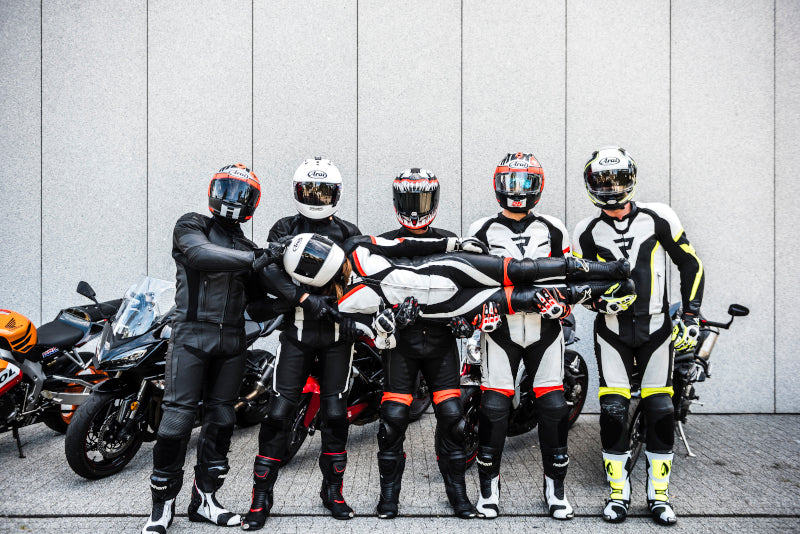 pięcioro motocyklistów trzyma motocyklistkę w kombinezonie